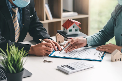 Business Meeting Discussing Mortgage with Model Houses and Calculator